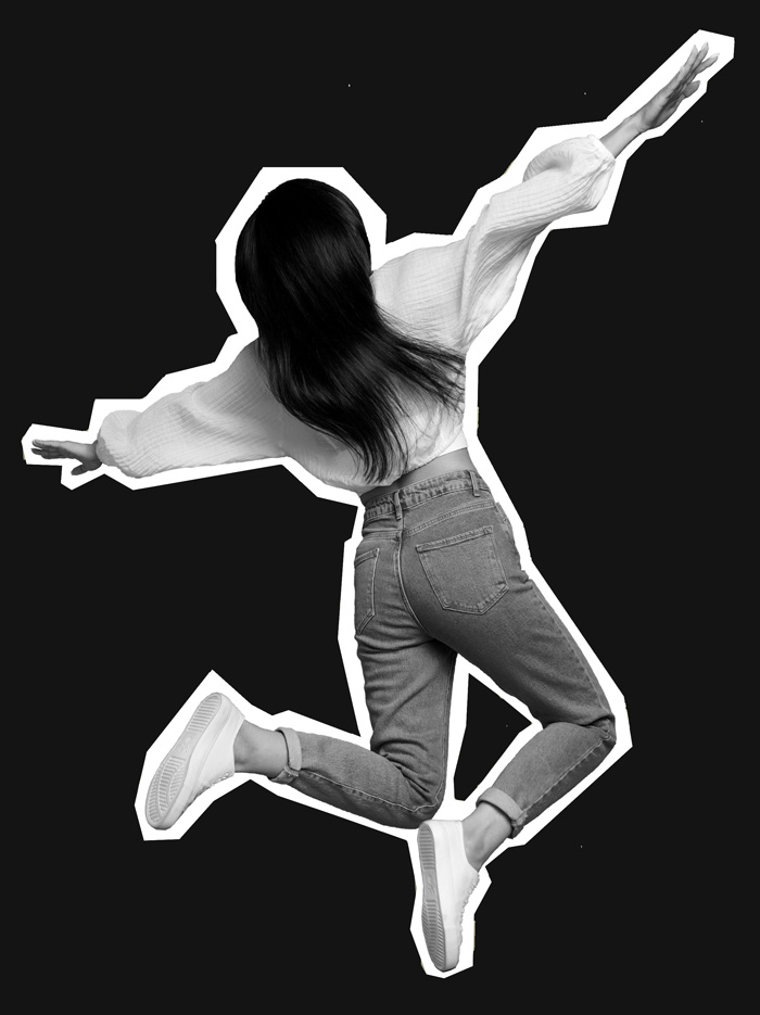 Person with long dark hair wearing a light sweater, jeans, and white sneakers jumping with arms and legs spread against a black background with a white outline.
