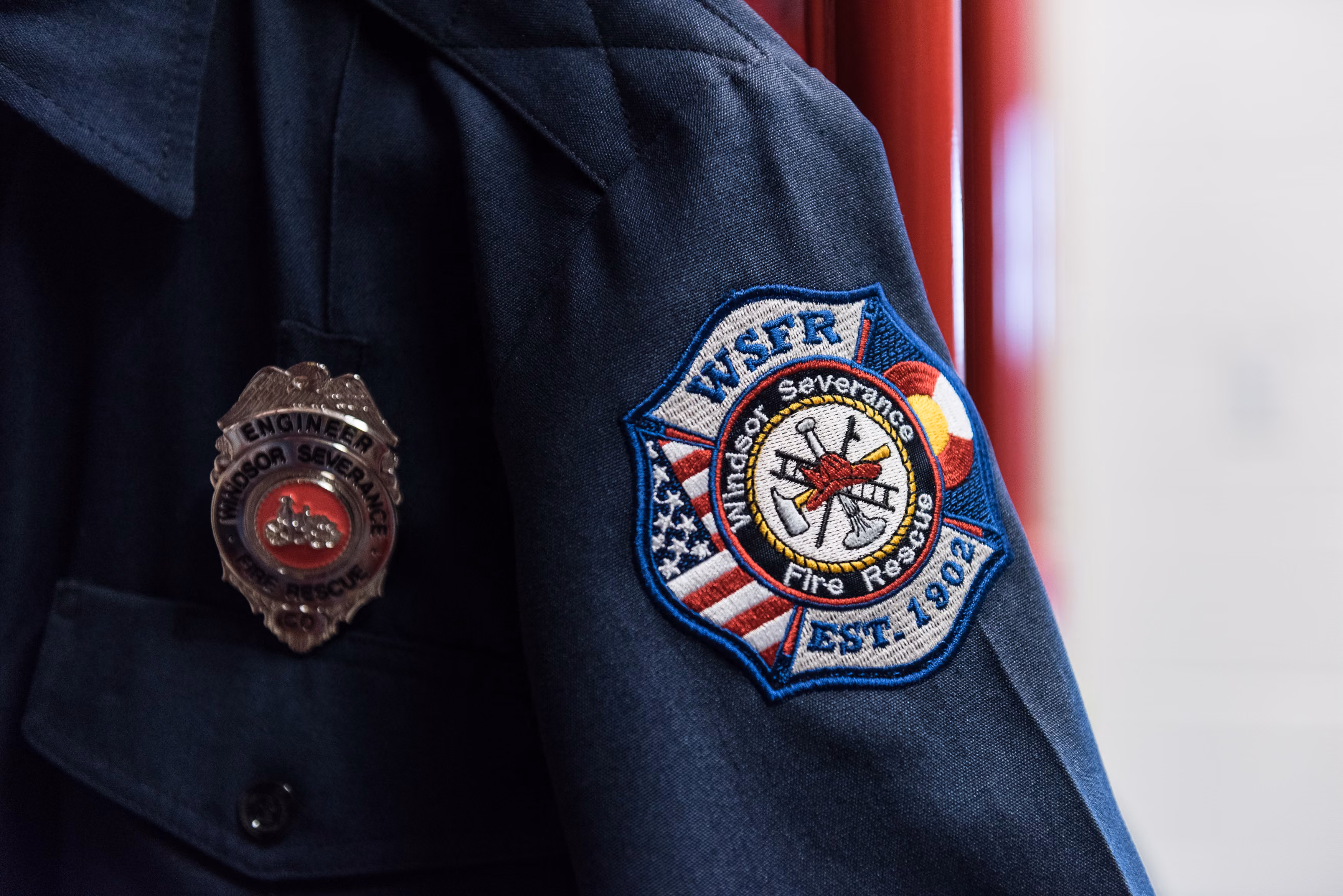 Close-up of dark firefighter jacket with Windsor-Severance Fire Rescue badge and engineer shield.