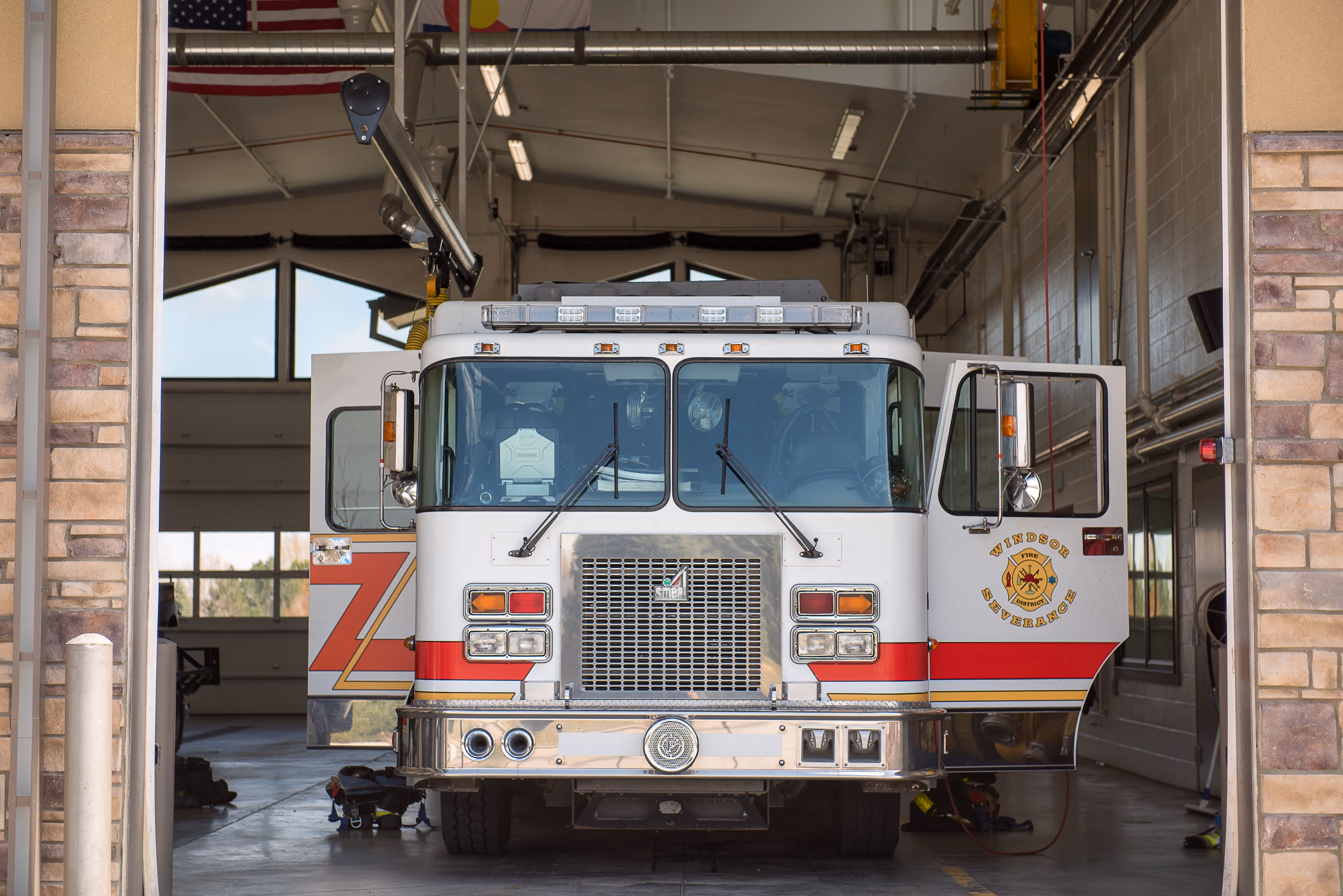 Front view of a white and red Windsor-Severance fire truck with open doors inside a fire station.