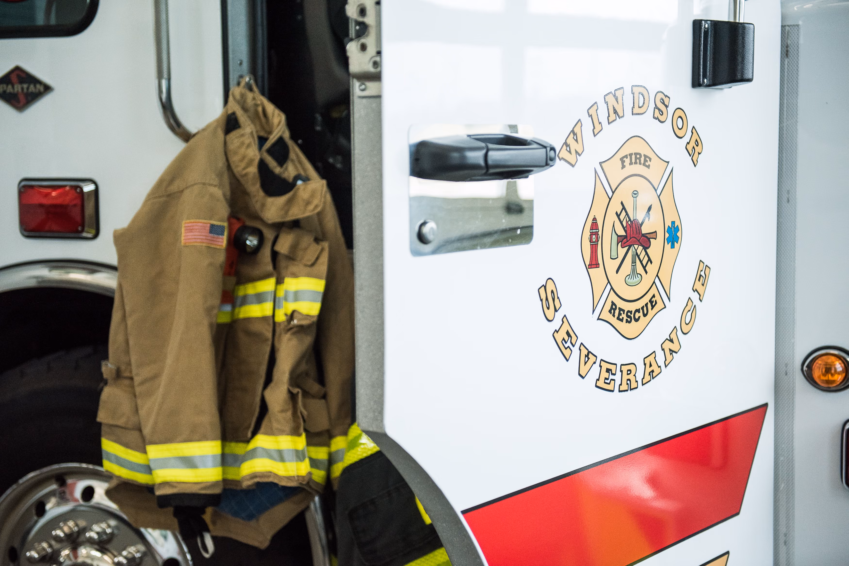 Firefighter turnout jacket hanging on the open door of a Windsor Severance fire rescue truck.