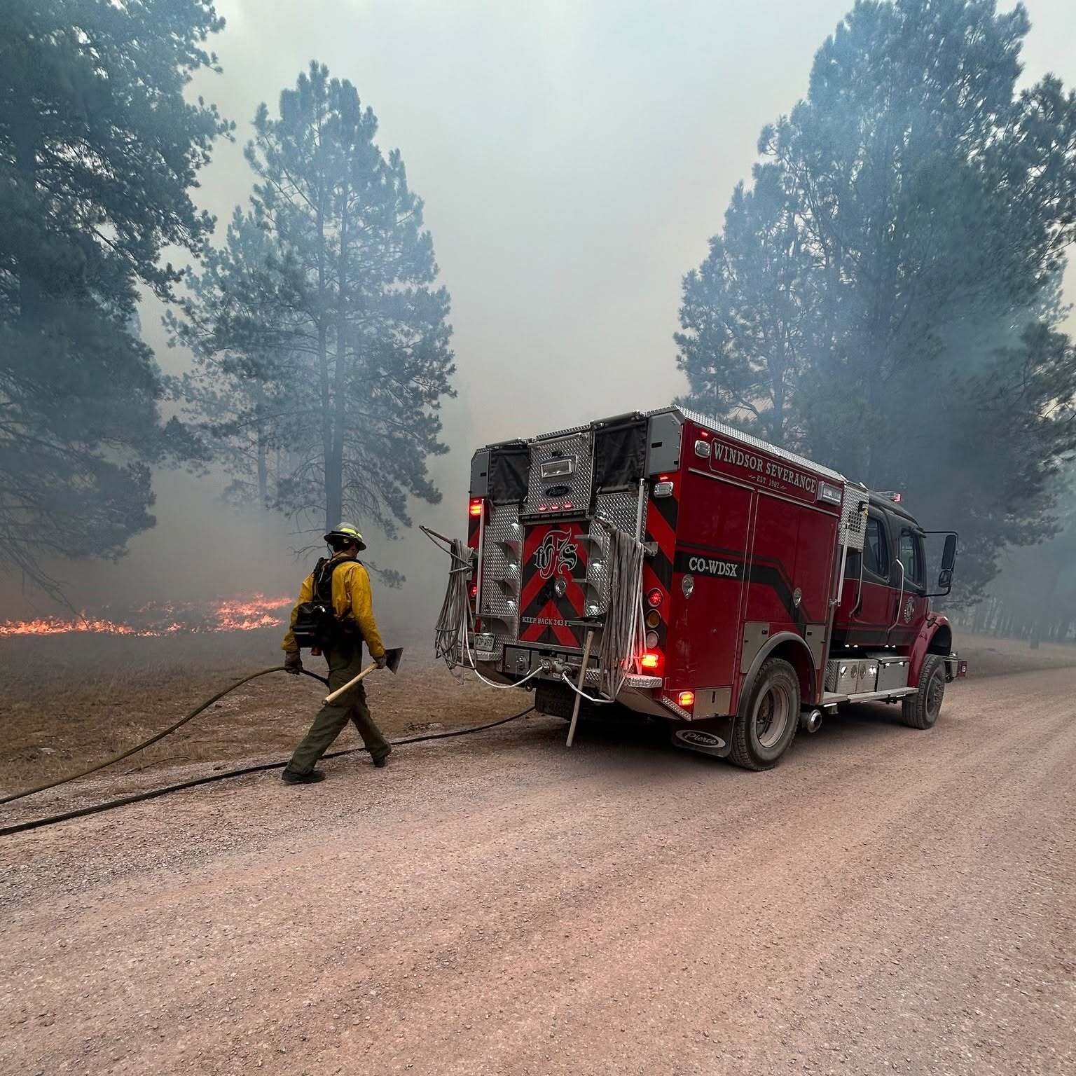 Windsor Severance Firefighter with firetruck in front of wildland fire
