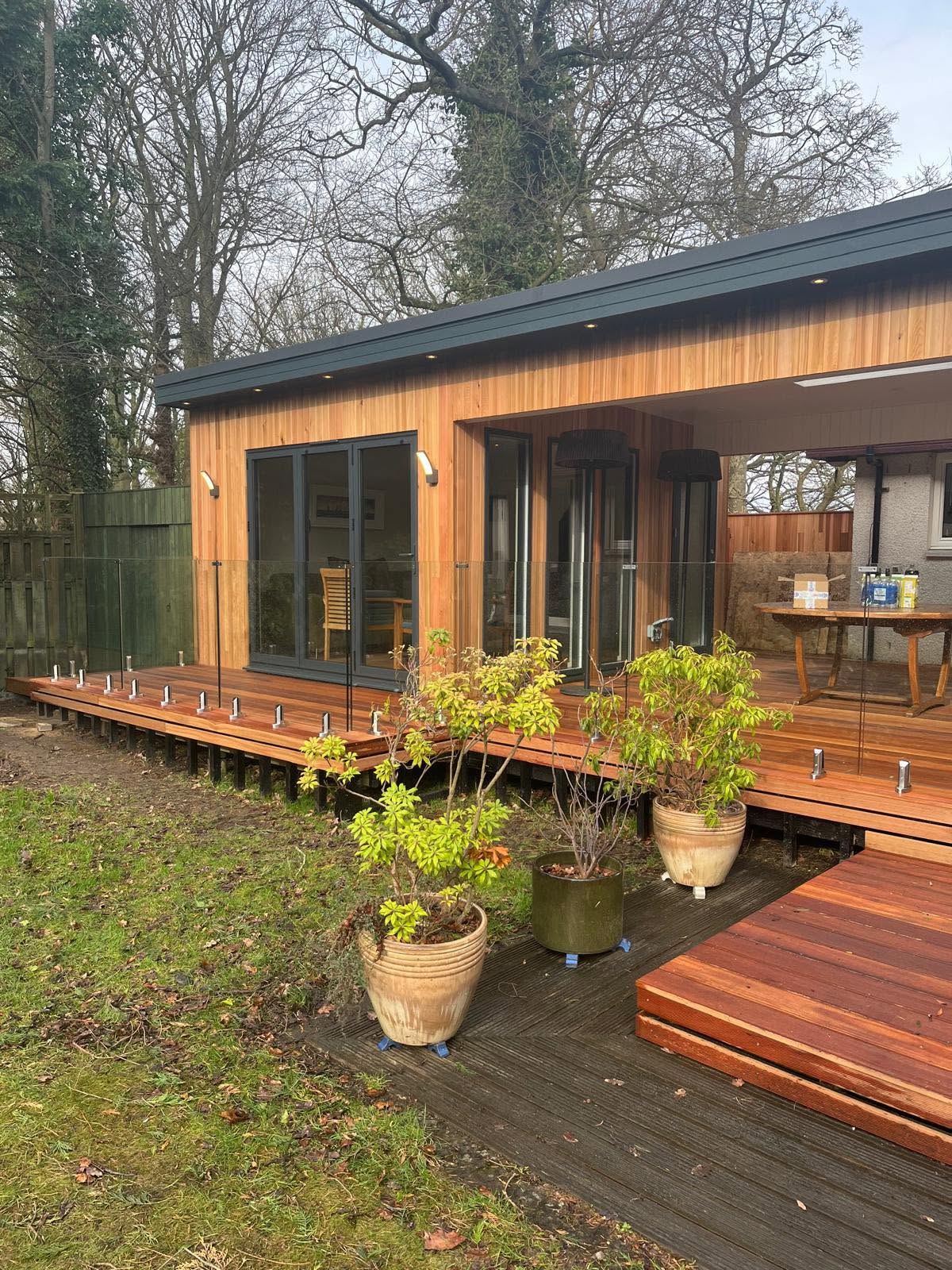 Frameless glass balustrade panels running along a timber garden room deck