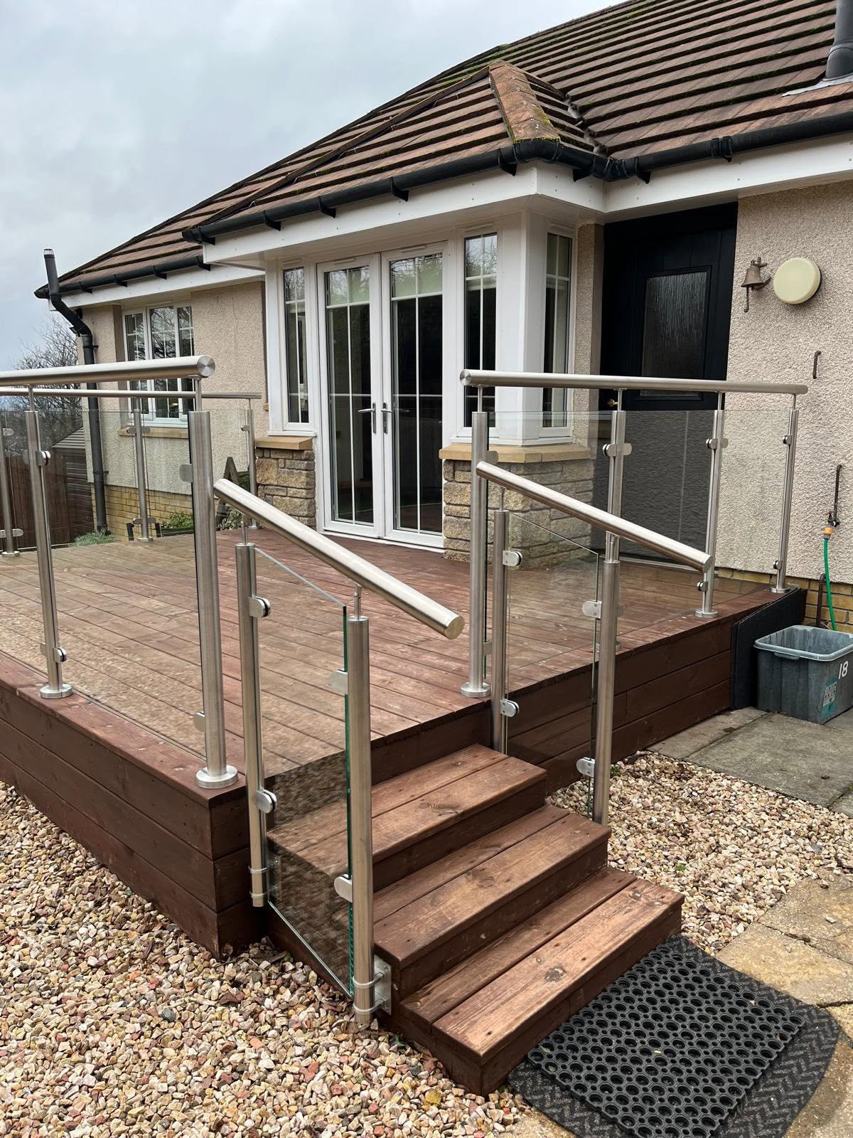 Glass balustrade with stainless steel posts on a timber decked patio and steps