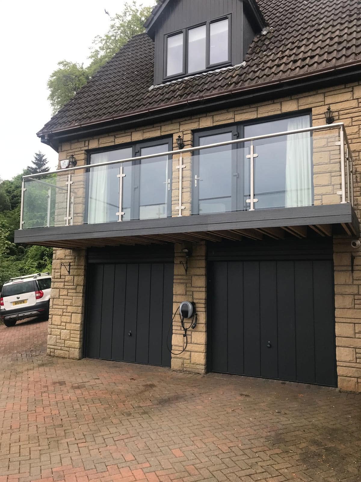 Glass balustrade balcony above garage doors on a stone built house
