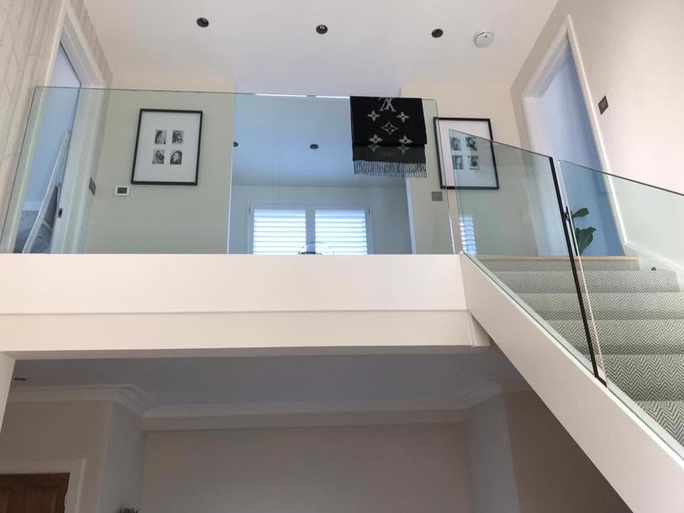Frameless glass balustrade panels along an internal landing and staircase