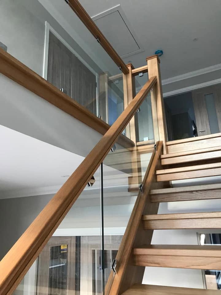 Glass balustrade panels with oak handrail on an open plan wooden staircase