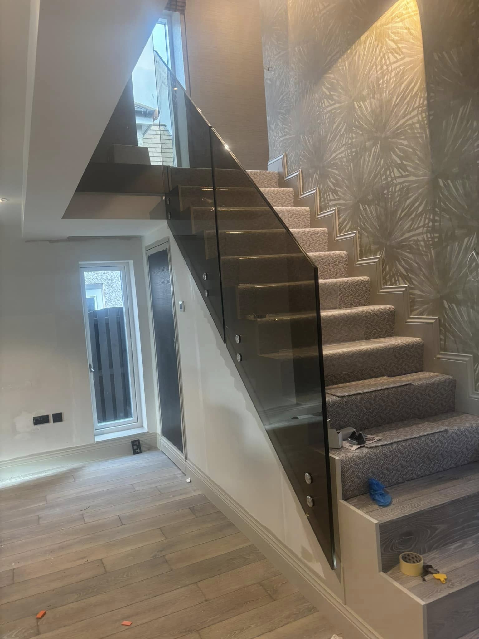 Frameless glass balustrade panels installed along a carpeted staircase