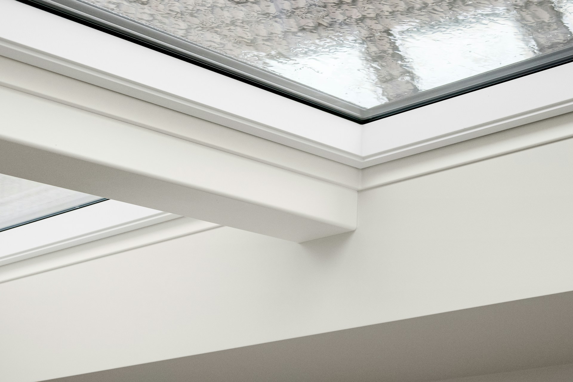 Stock photo, close-up of a white framed skylight window corner in rain