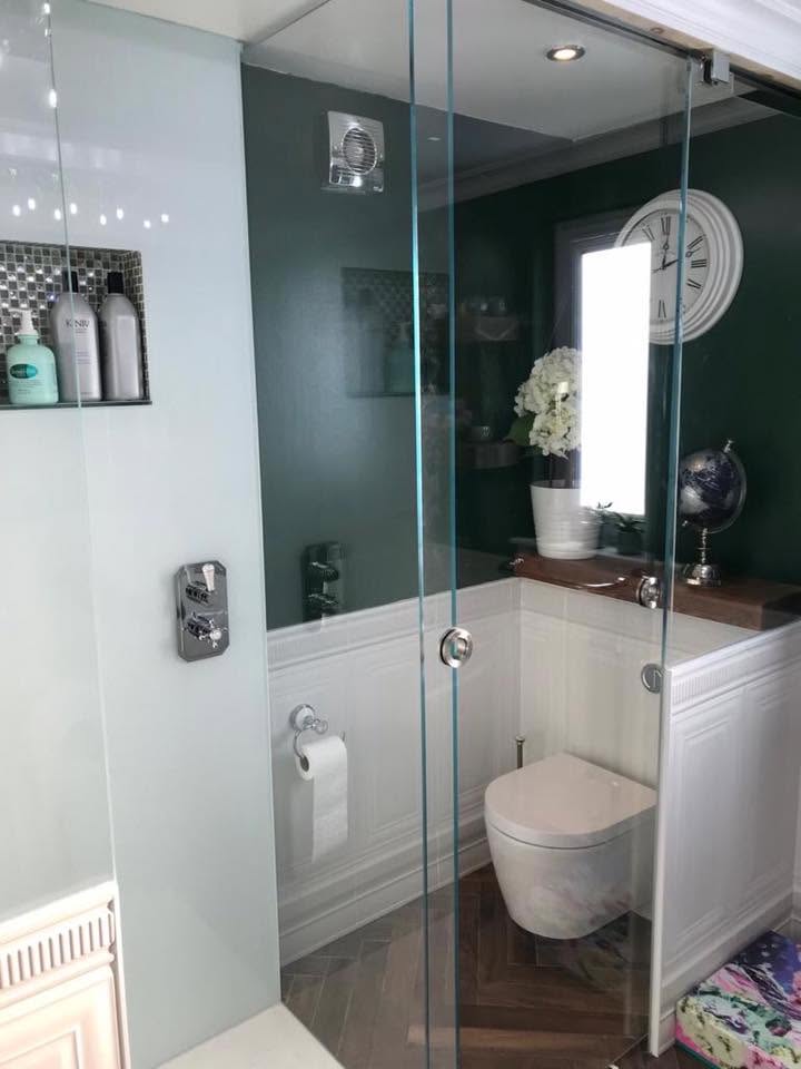 Sliding glass shower screen dividing a walk-in shower from a green bathroom