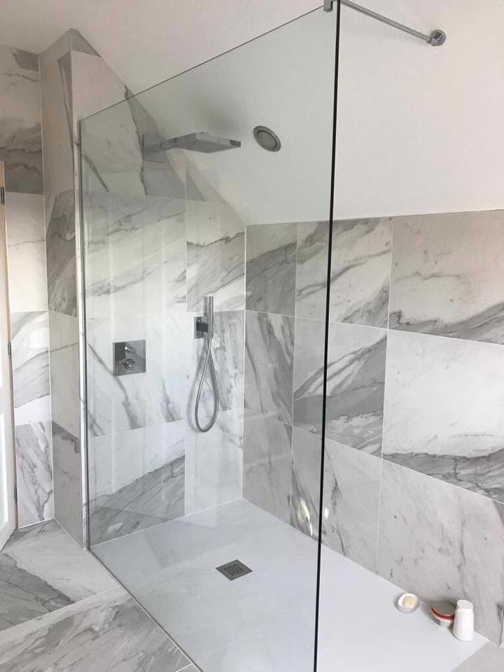 Fixed glass shower screen in a walk-in wet room with grey marble tiles