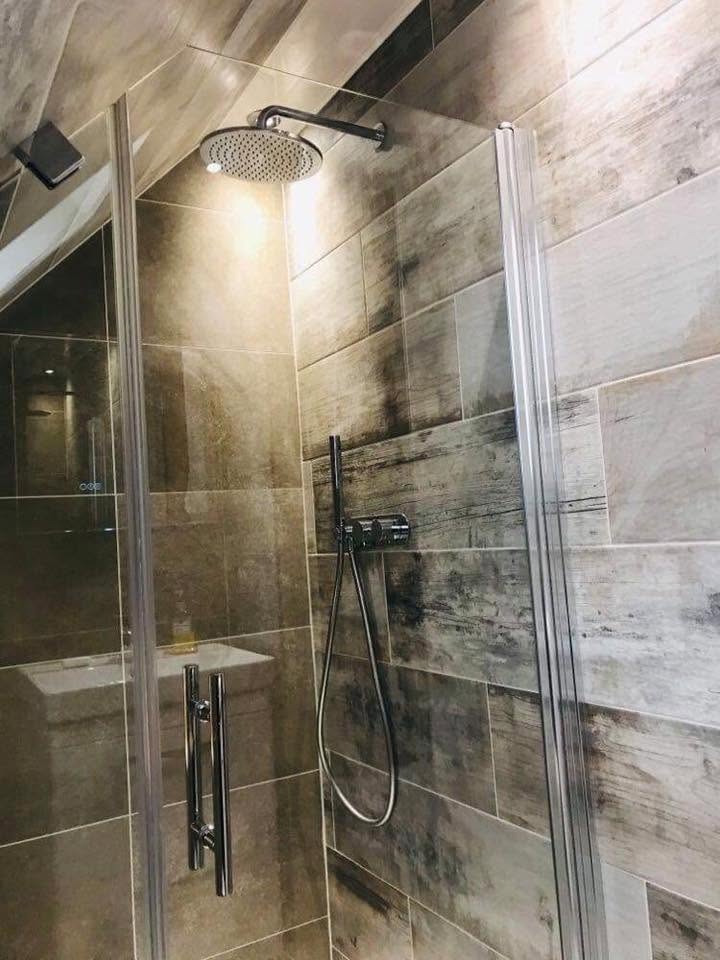 Glass shower enclosure with chrome fittings against wood-effect tiling