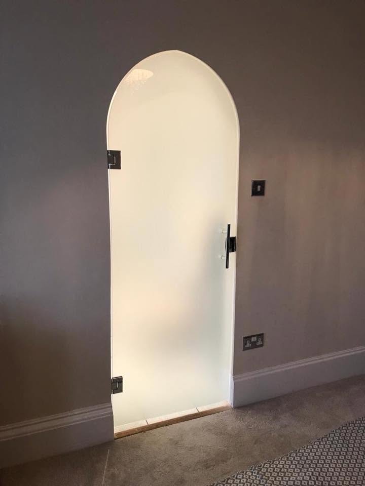 Custom arched frosted glass door with black hinges in a hallway