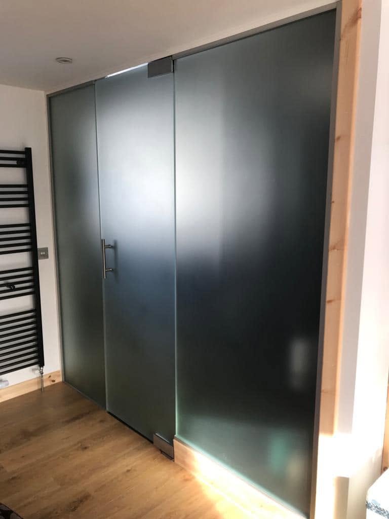 Frosted frameless glass partition wall with a pull handle door and wood floor