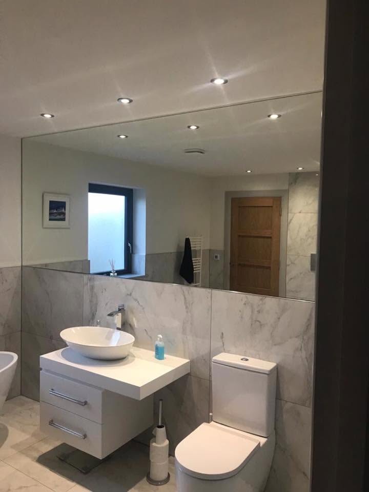 Large wall mirror above a marble tiled bathroom vanity with vessel sink