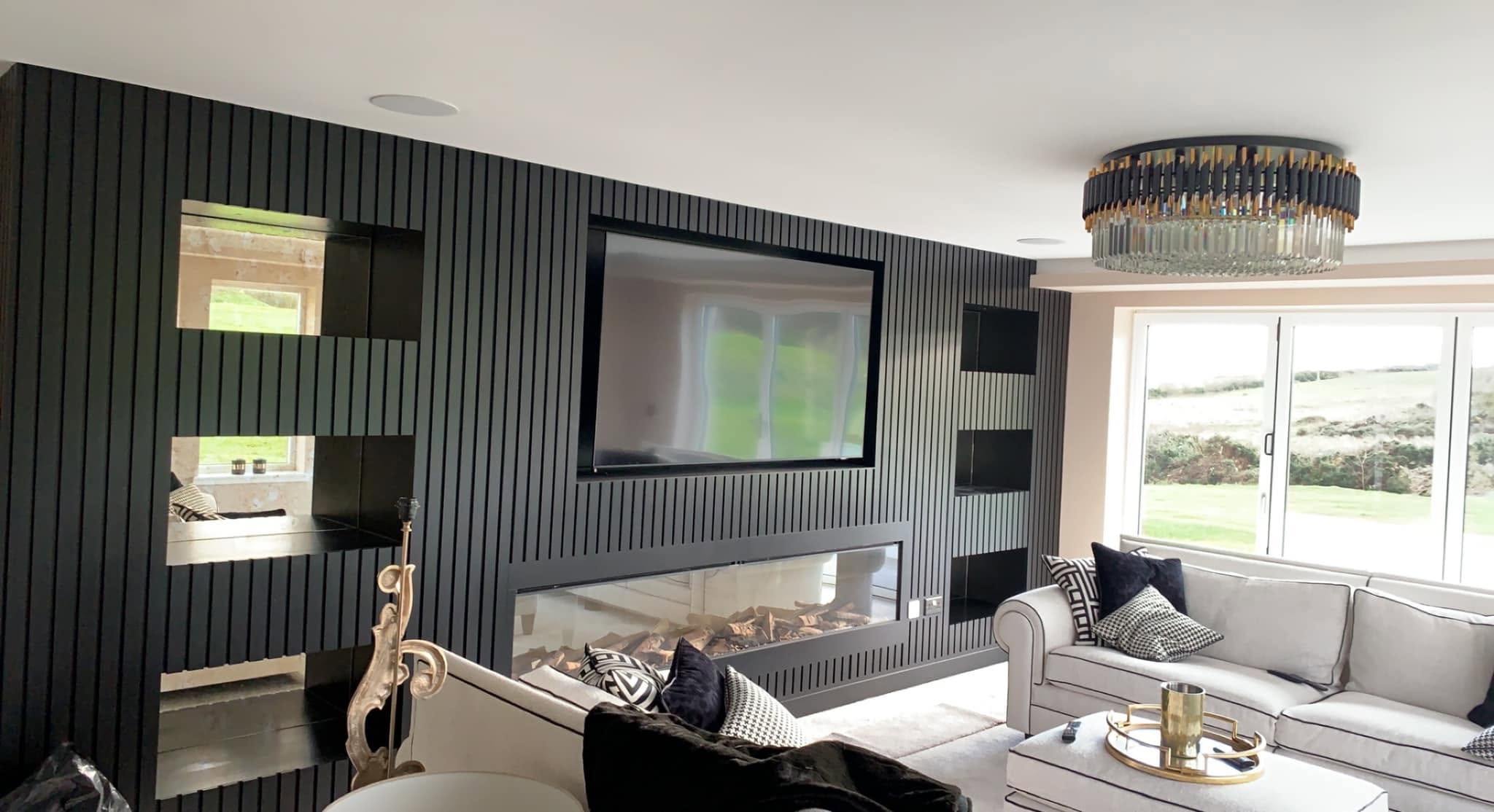 Mirrored recessed alcove shelving built into a dark slatted media wall
