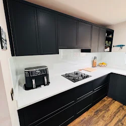 White glass splashback behind a gas hob in a black shaker kitchen