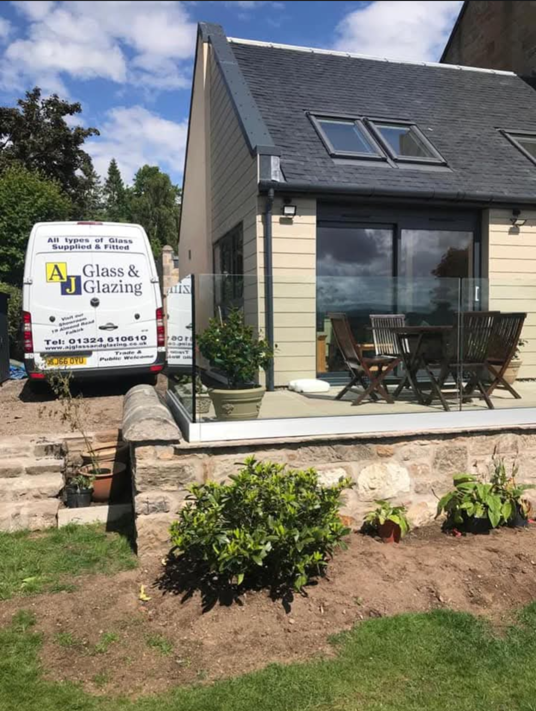 Frameless glass balustrade on a garden patio with AJ Glass and Glazing van behind
