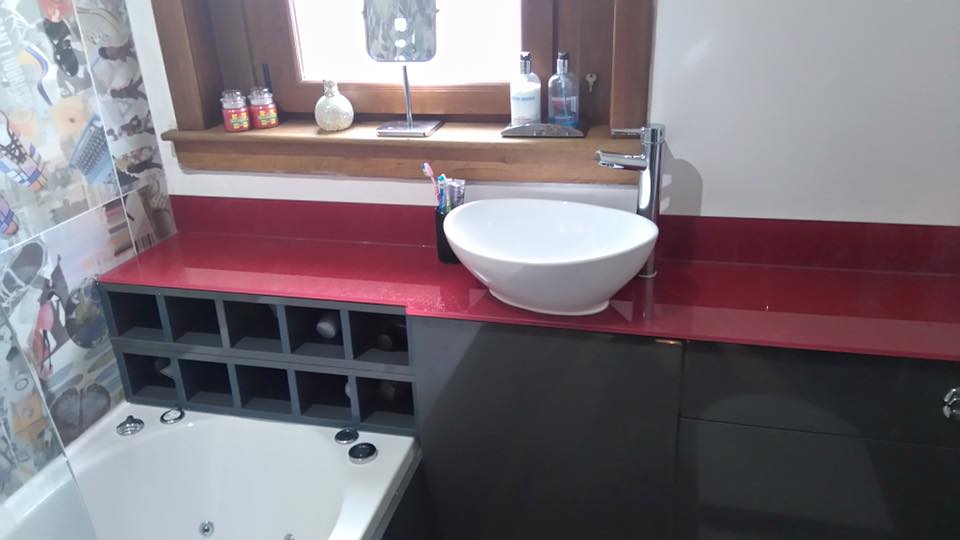 Metallic red glass worktop with a white countertop basin in a bathroom