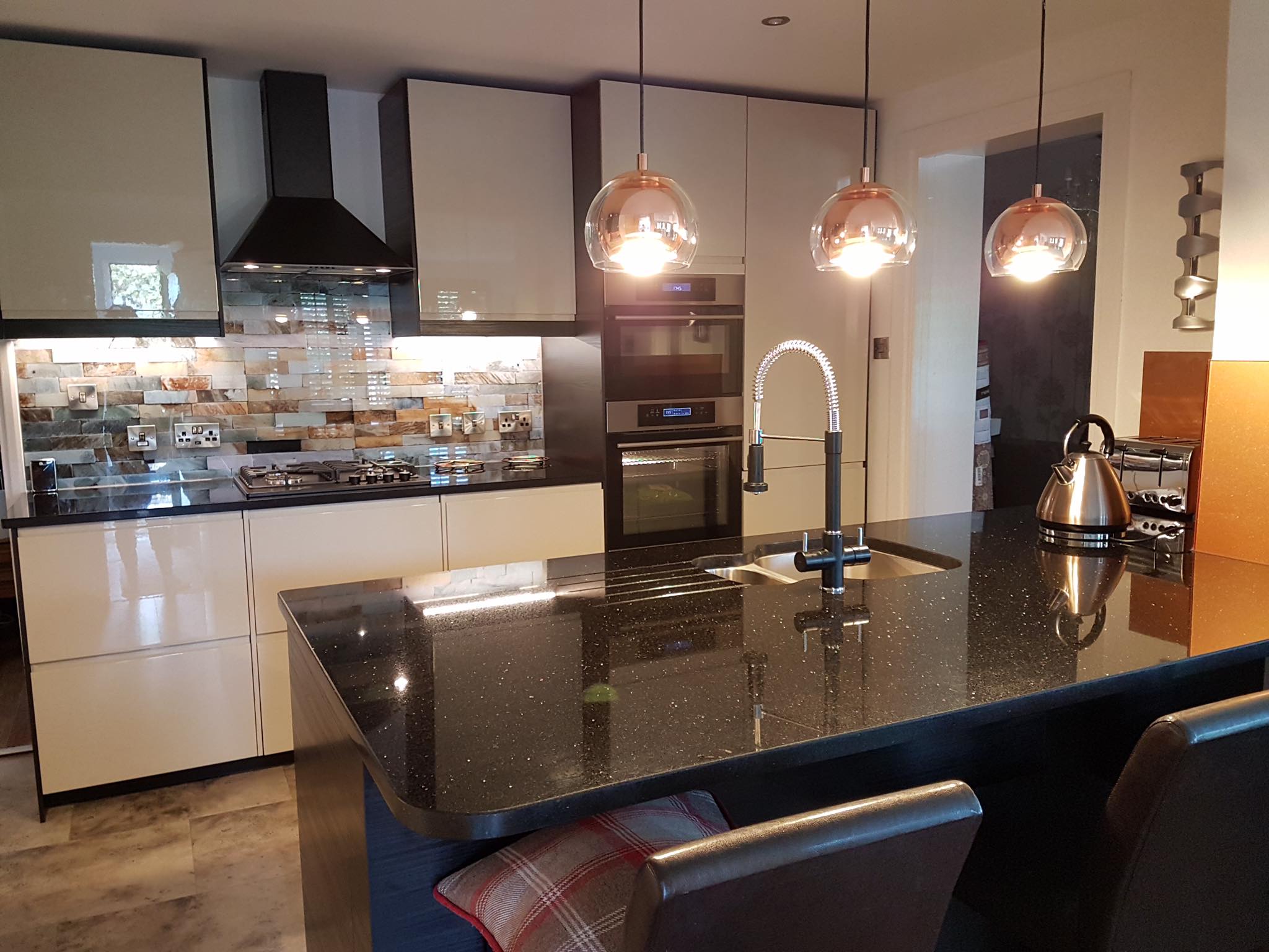 Brick effect splashback behind the hob, with a copper glass panel by the kettle