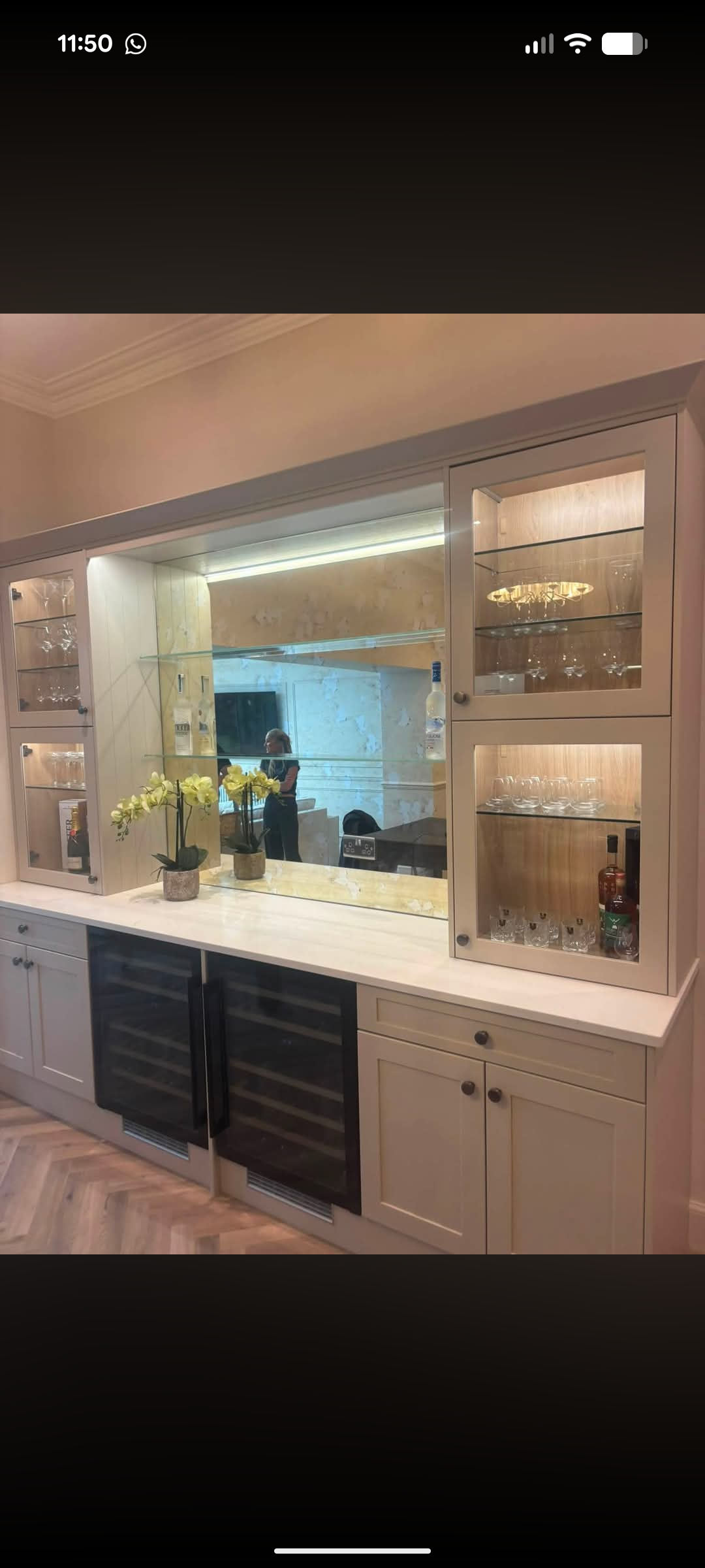 Mirrored glass splashback behind a fitted home bar with glass display cabinets