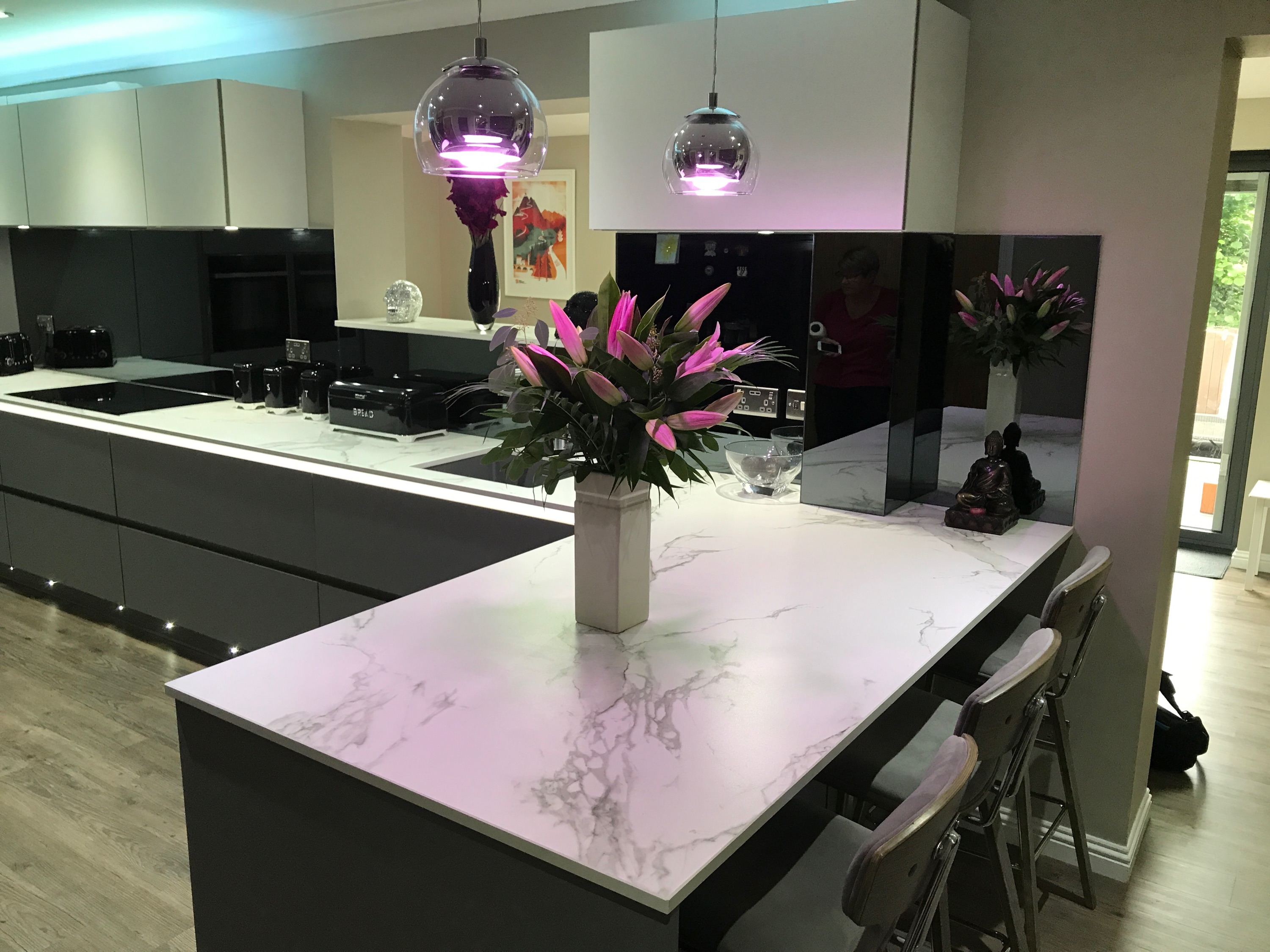 Grey mirror glass splashback beside a marble effect kitchen island breakfast bar