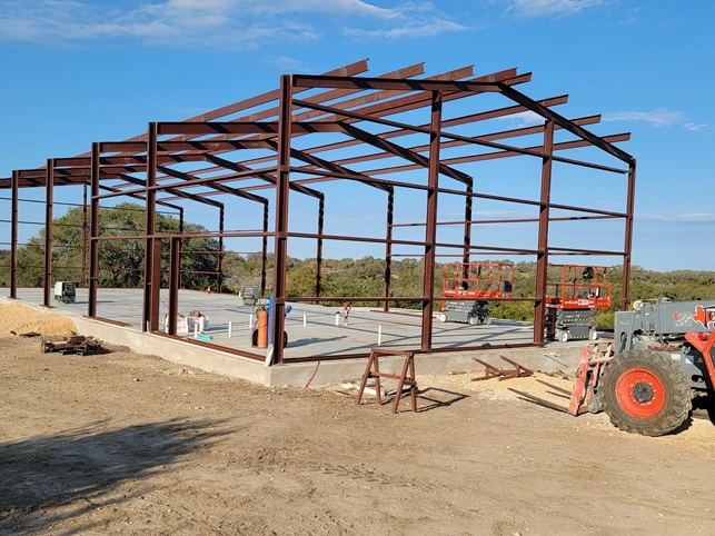 Red-oxide steel frame of a large building erected on a graded pad during construction