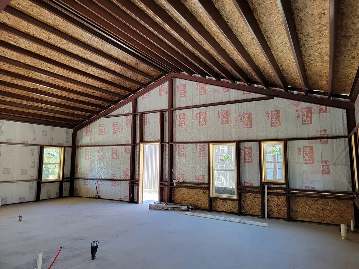 Exposed wood rafters and insulated wall panels inside a steel-framed home before interior finishes