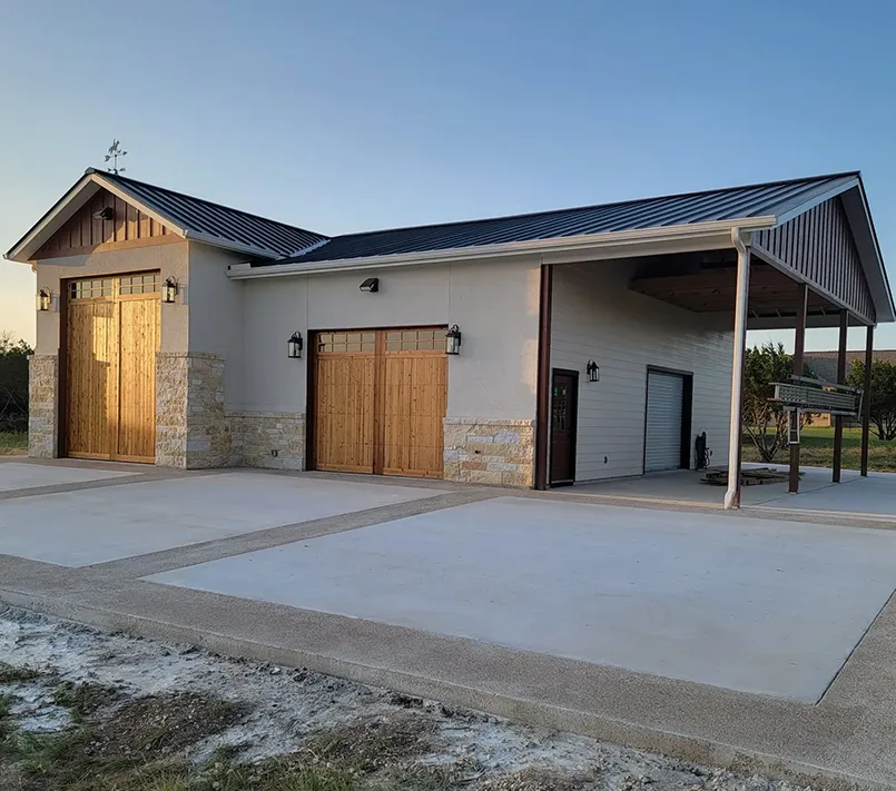 Detached workshop with timber carriage doors, limestone accents and a covered equipment bay