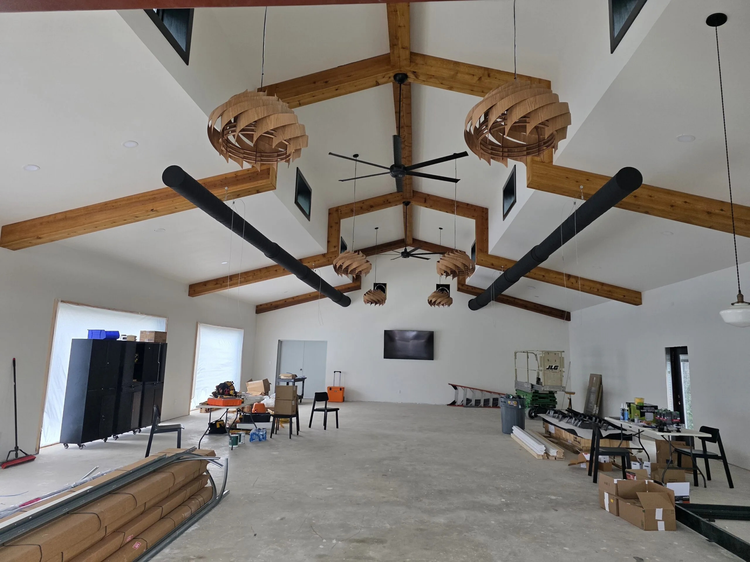 Vaulted barndominium interior with exposed cedar beams and timber pendant lights by Hill Country Building & Renovation