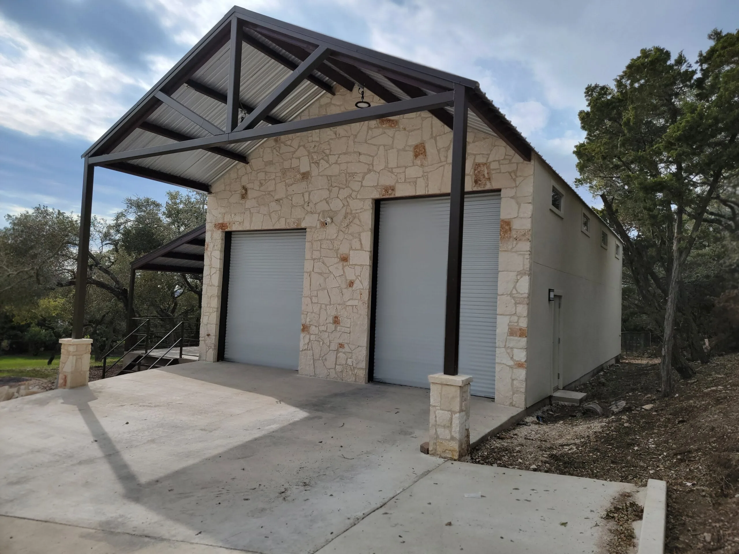 Completed RV garage with a limestone facade, two tall roll-up doors and an exposed steel gable frame