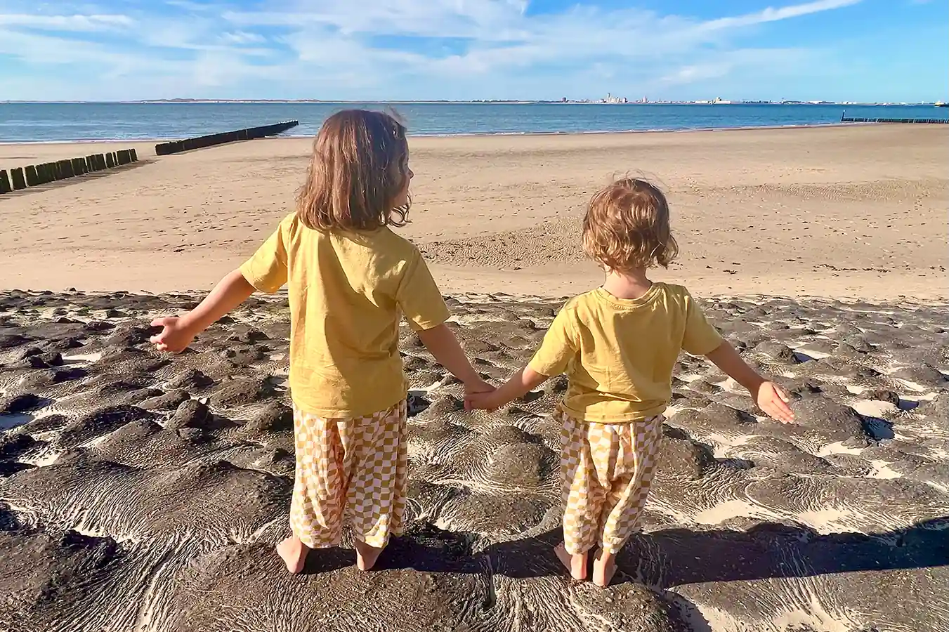 Zwei Kinder laufen Hand in Hand zum Strand