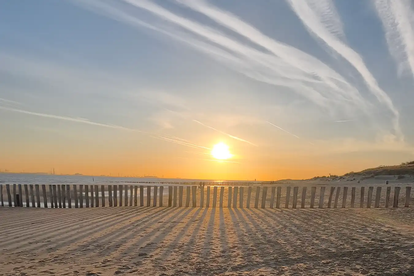 Sonnenuntergang am Strand von Breskens mit Buhnen im Sand