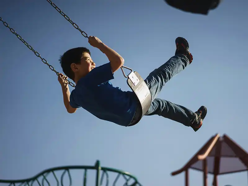 Kind schaukelt auf einem Spielplatz (Symbolbild)