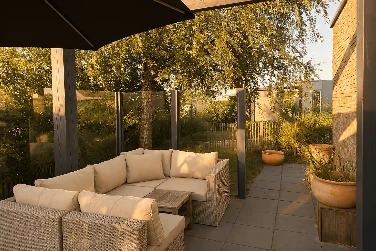 Überdachte Terrasse der Ferienlodge Zeeland mit Loungemöbeln und Blick in den Garten