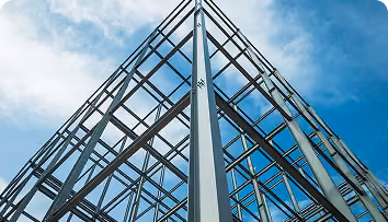 Steel framework structure viewed from below against a blue sky with white clouds.