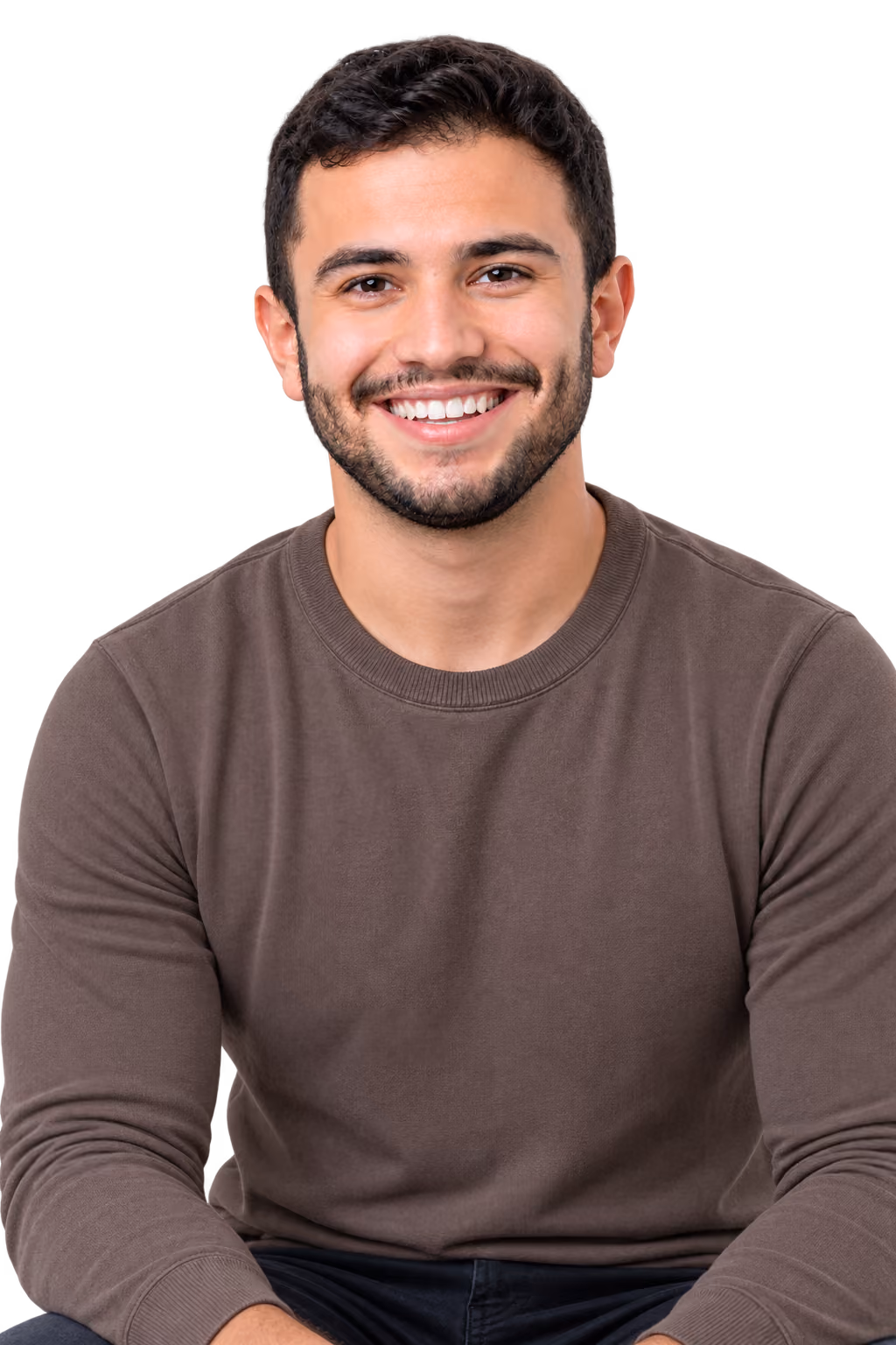 Smiling young man with curly hair wearing a polo shirt, seated indoors with a bright background.