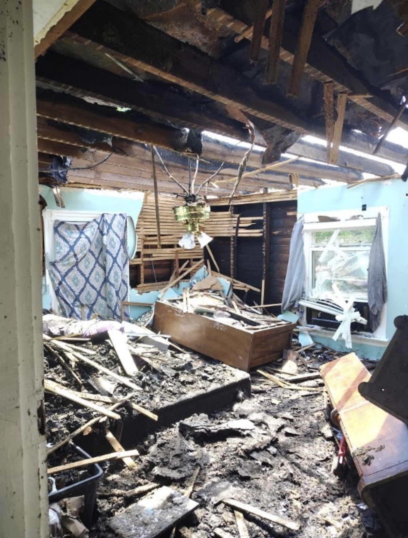 Fire-damaged interior with severe smoke and structural loss during restoration assessment.