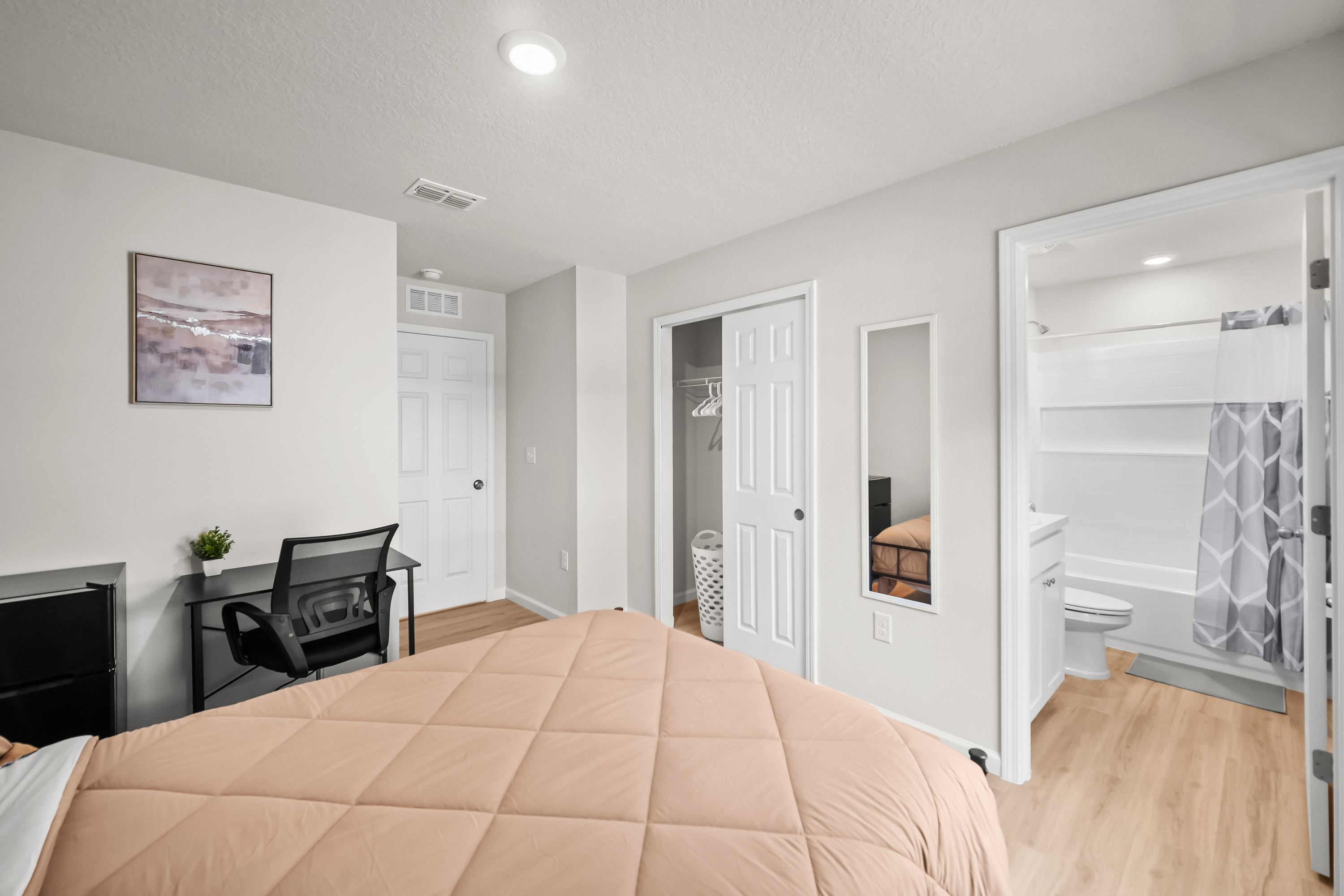 Photo of a bedroom—along with en-suite bathroom in view—in a co-living home. 