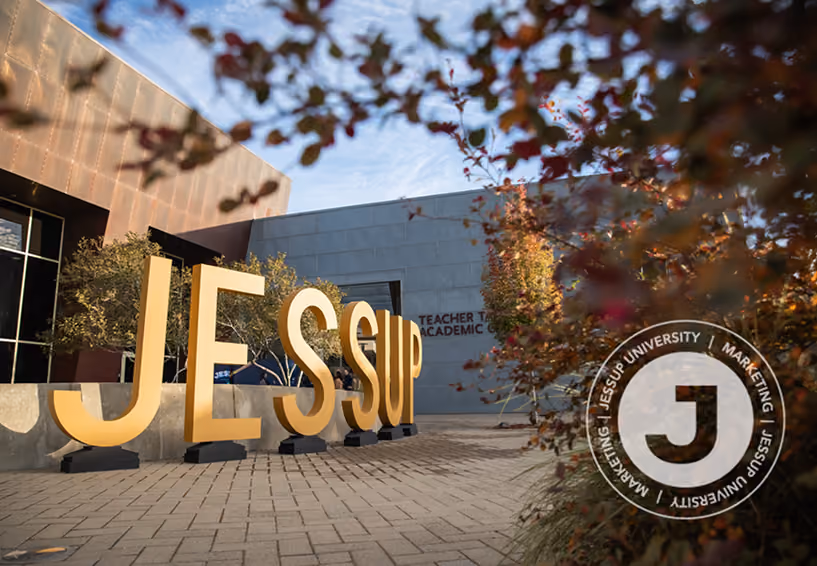 Large yellow letters spelling Jessup outside a university building with autumn foliage.