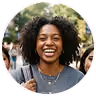 Smiling woman with curly hair standing outdoors with people blurred in the background.
