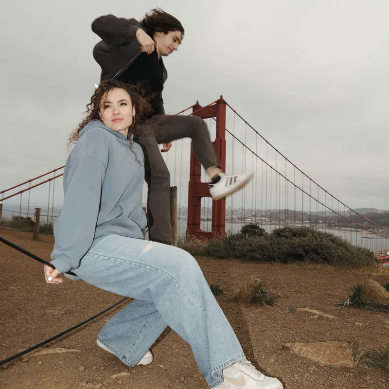 Two people wearing casual clothes posing playfully with the Golden Gate Bridge in the background.