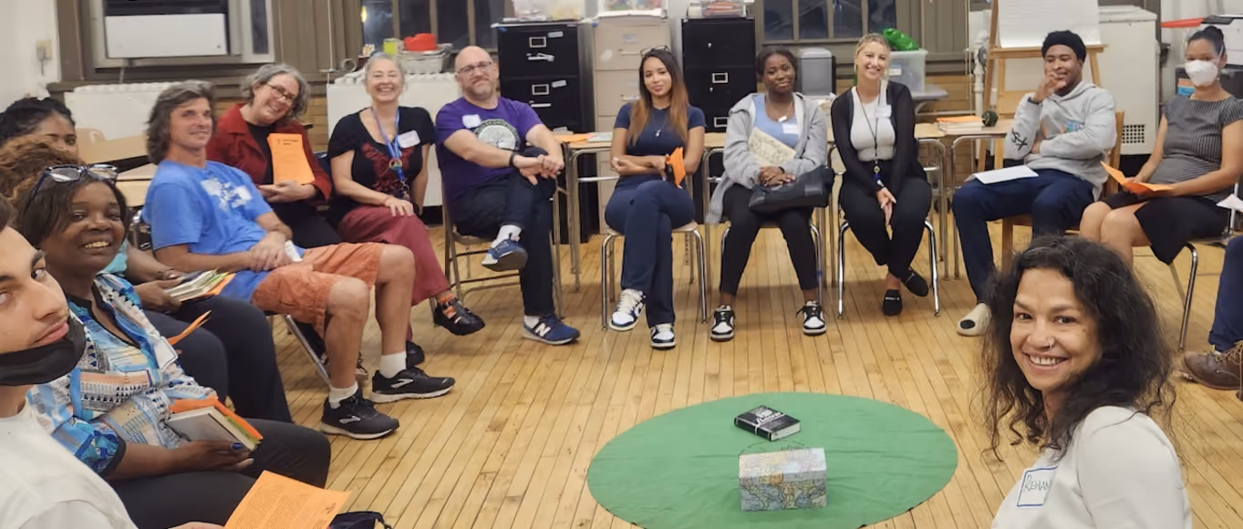 Diverse group of adults seated in a circle during a school meeting