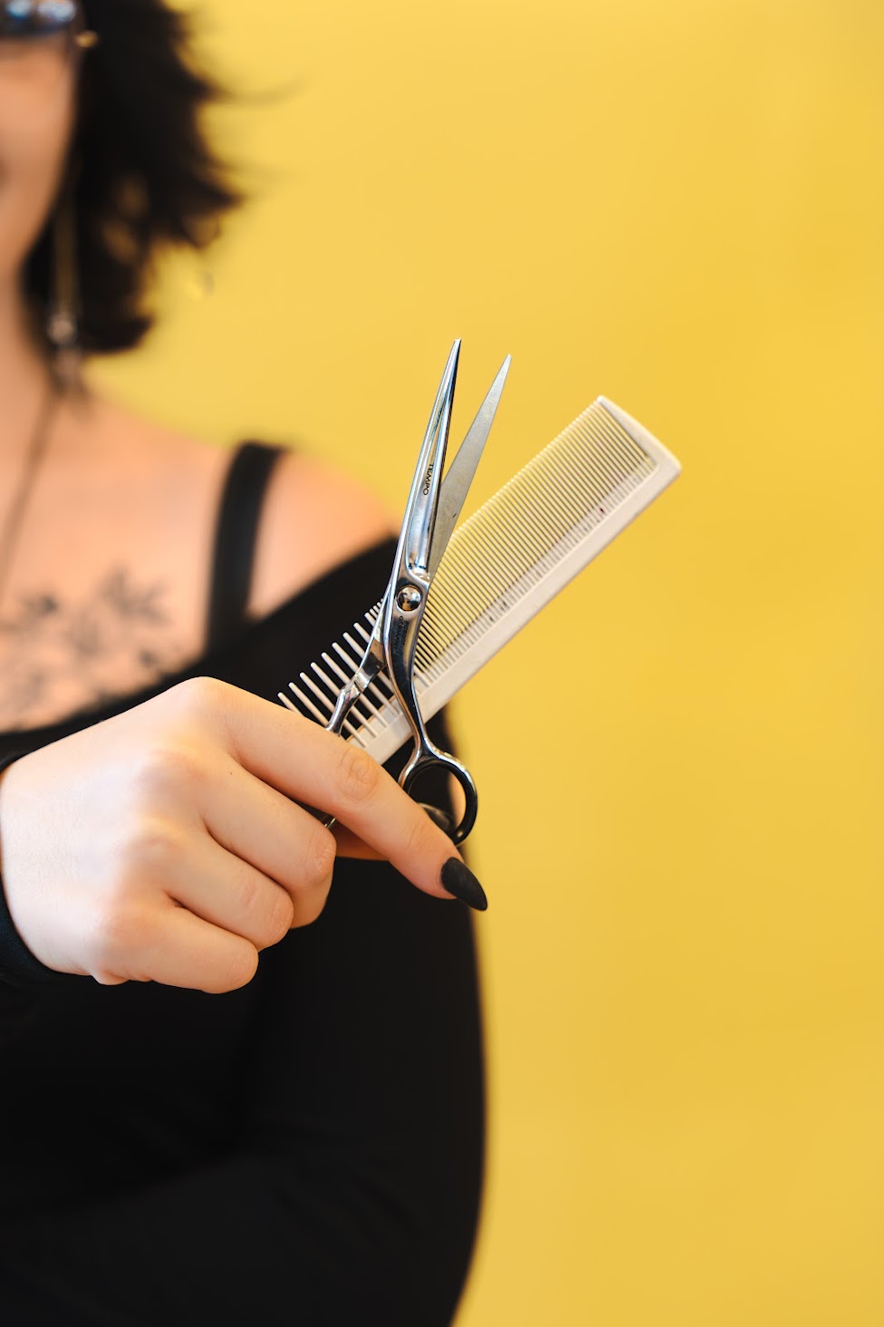 Cosmetology student holding shears and a comb at OMNA Institute in Lynchburg, VA