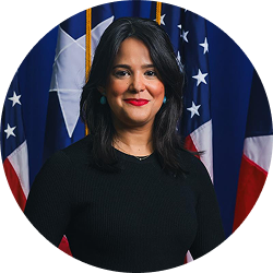 Official portrait of Natalia D. Catoni in a black top with U.S. and Puerto Rico flags behind her.