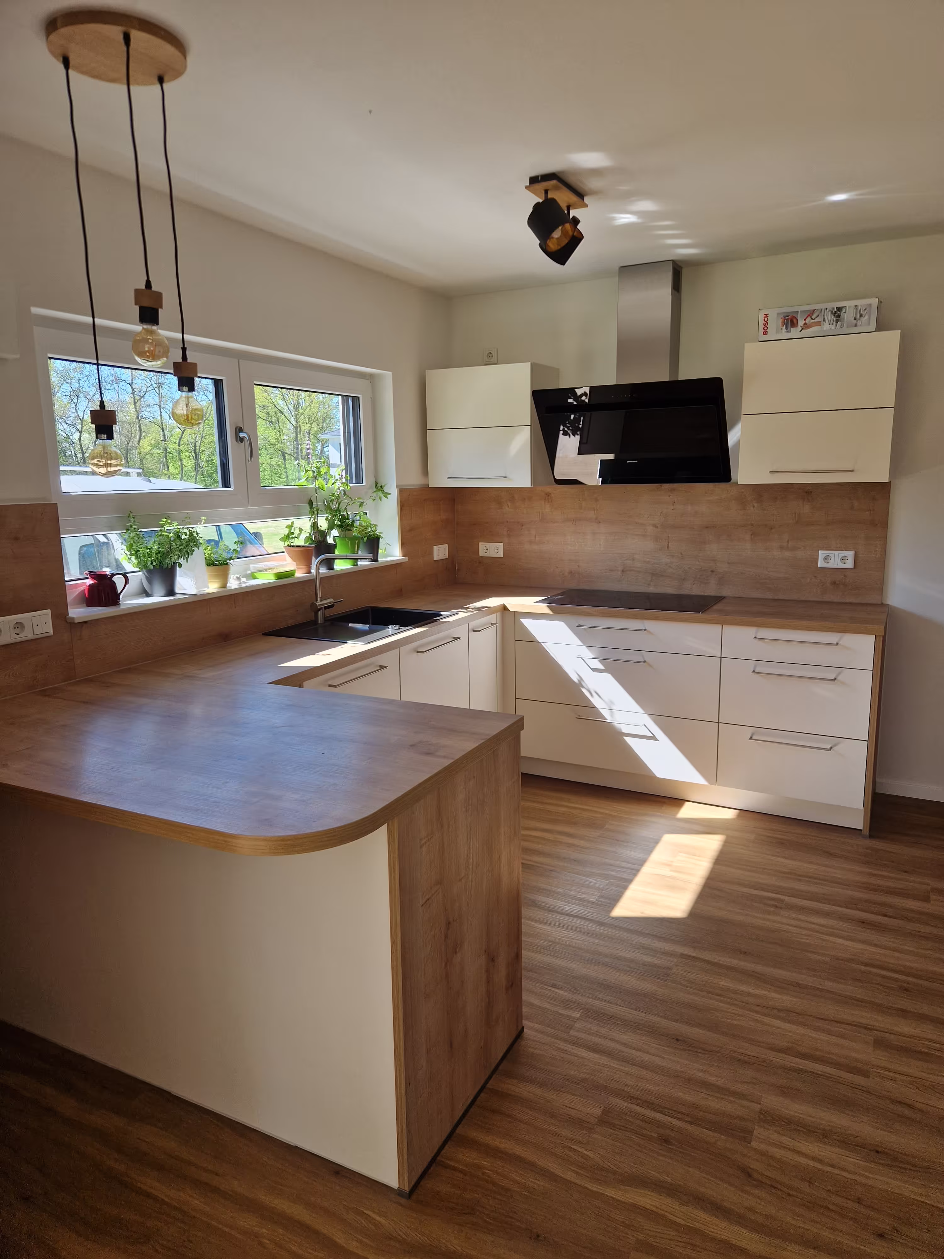 Fertig montierte Küche mit Kochinsel aus einem Projekt von Deutscher – Haus. Bau. Montage.