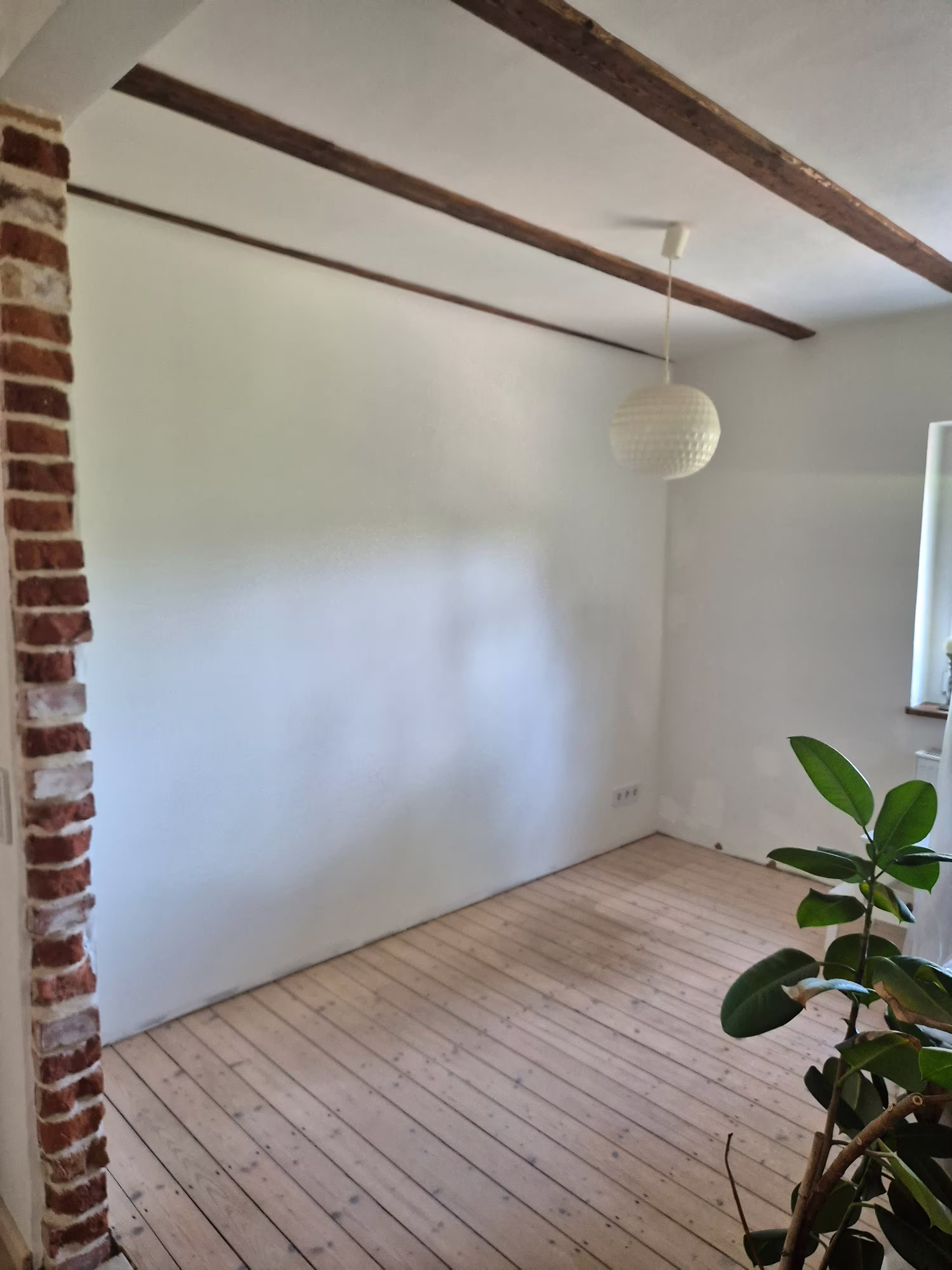 Wohnraum mit neuer Vorsatzwand in Trockenbauweise neben Ziegelmauerwerk