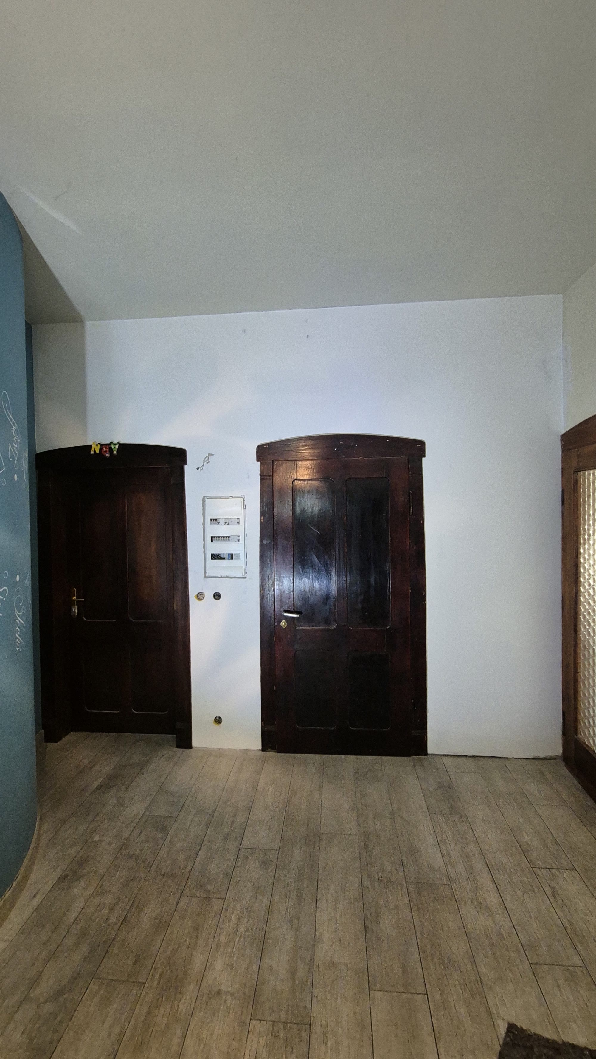 Renovierter Raum mit hell gestrichener Wand und dunklen Altbautüren