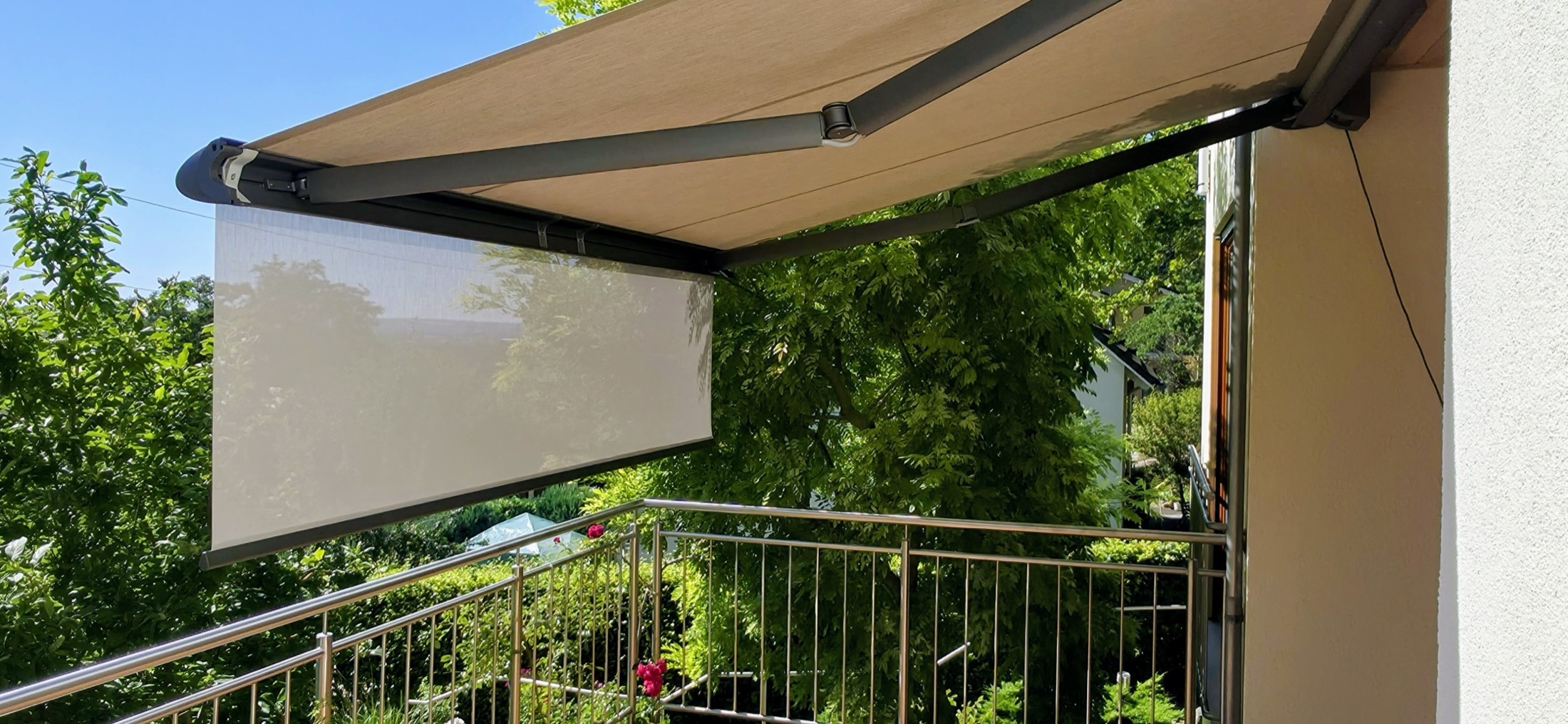 Beschatteter Balkonsitzplatz mit ausgefahrenem Sonnenschutztuch über der Terrasse