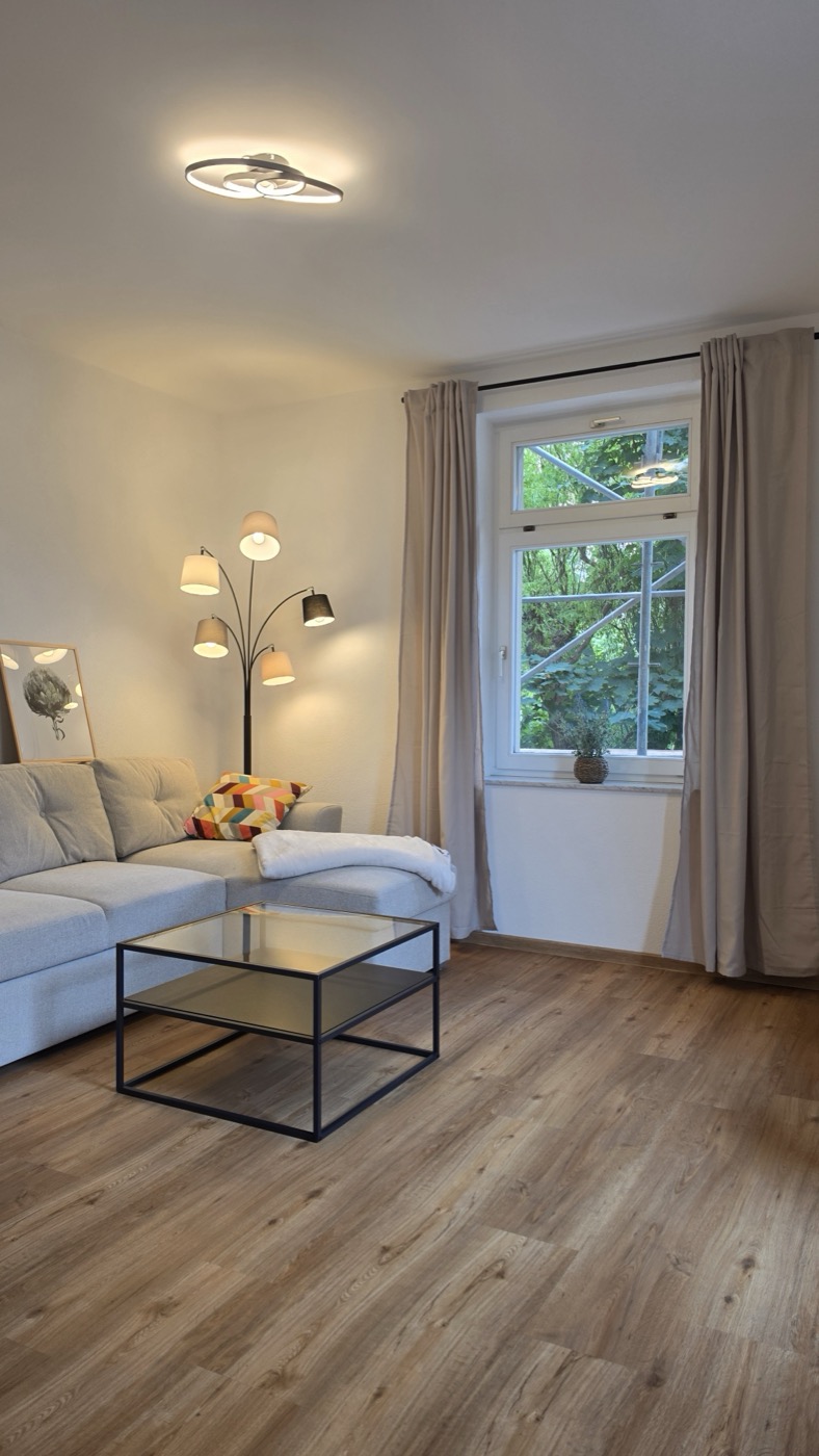 Helles Wohnzimmer mit Sofa und neu verlegtem Holzboden – abgeschlossenes Projekt von Deutscher – Haus. Bau. Montage.