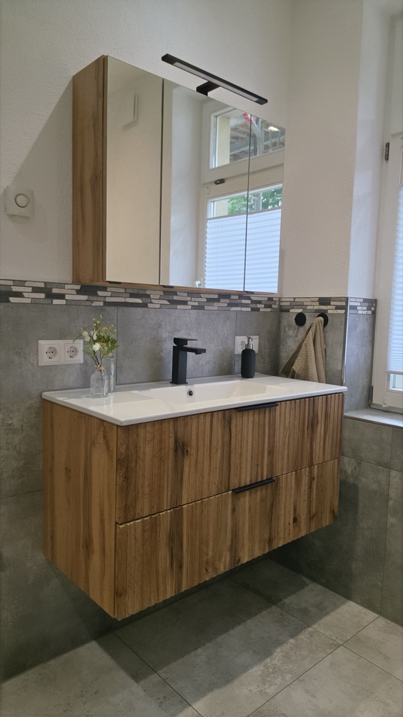 Neu gebautes Badezimmer mit Holz-Waschtisch, Spiegelschrank und schwarzer Armatur